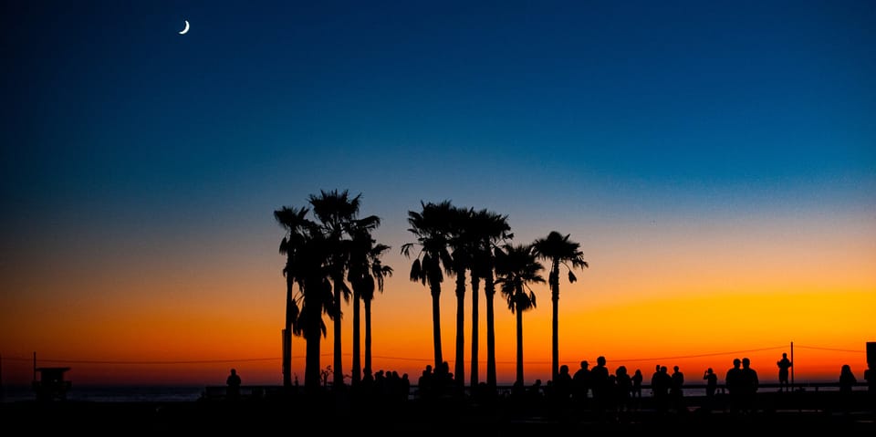 Sunset in Venice, California with crescent moon visible and people silhouetted. Photo by Anthony Citrano.
